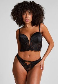 Zwarte lingerie set met een satijnen en kanten bustier met beugel, een gestructureerd ontwerp en verstelbare bandjes. Bijpassende kanten string met een decoratief accent.