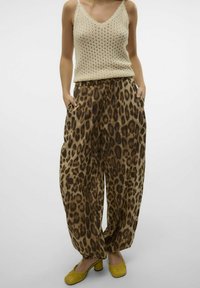 Beige strikket tanktop med V-hals og tynde stropper, kombineret med løse bukser i leopardmønster i brune og sorte nuancer, samt gule flade sko.