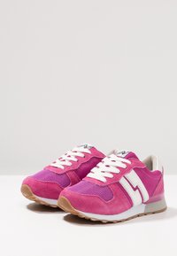 Scarpe da ginnastica rosa realizzate in materiali mesh e suede. Presentano lacci bianchi, un design a saetta bianca e suole in gomma testurizzata.