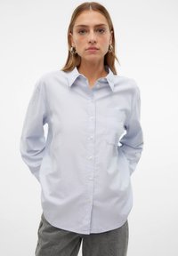 Camicia a maniche lunghe azzurro chiaro con chiusura a bottoni, colletto e taschino sul lato sinistro del petto. Realizzata in tessuto liscio con una vestibilità comoda.