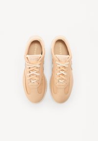 Pehmea pehmekollane värv sneakerid, mille peal on sile nahk, kontrastsed beežid nöörid ja tekstureeritud kummist tald. Omab All-Star logo keele peal.