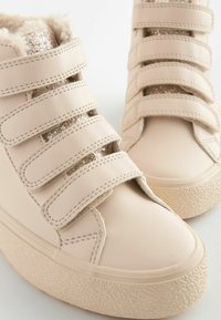 Beige hoge sneakers met faux fur voering, glinsterende accenten en verstelbare klittenbandsluitingen. Getextureerde rubbersole en glad bovendeel van synthetisch materiaal.