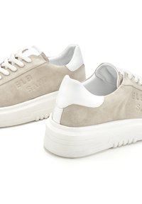 Sneakers in suede beige con dettagli in pelle bianca, lacci piatti e branding in rilievo. Suola in gomma bianca spessa con dettagli testurizzati.