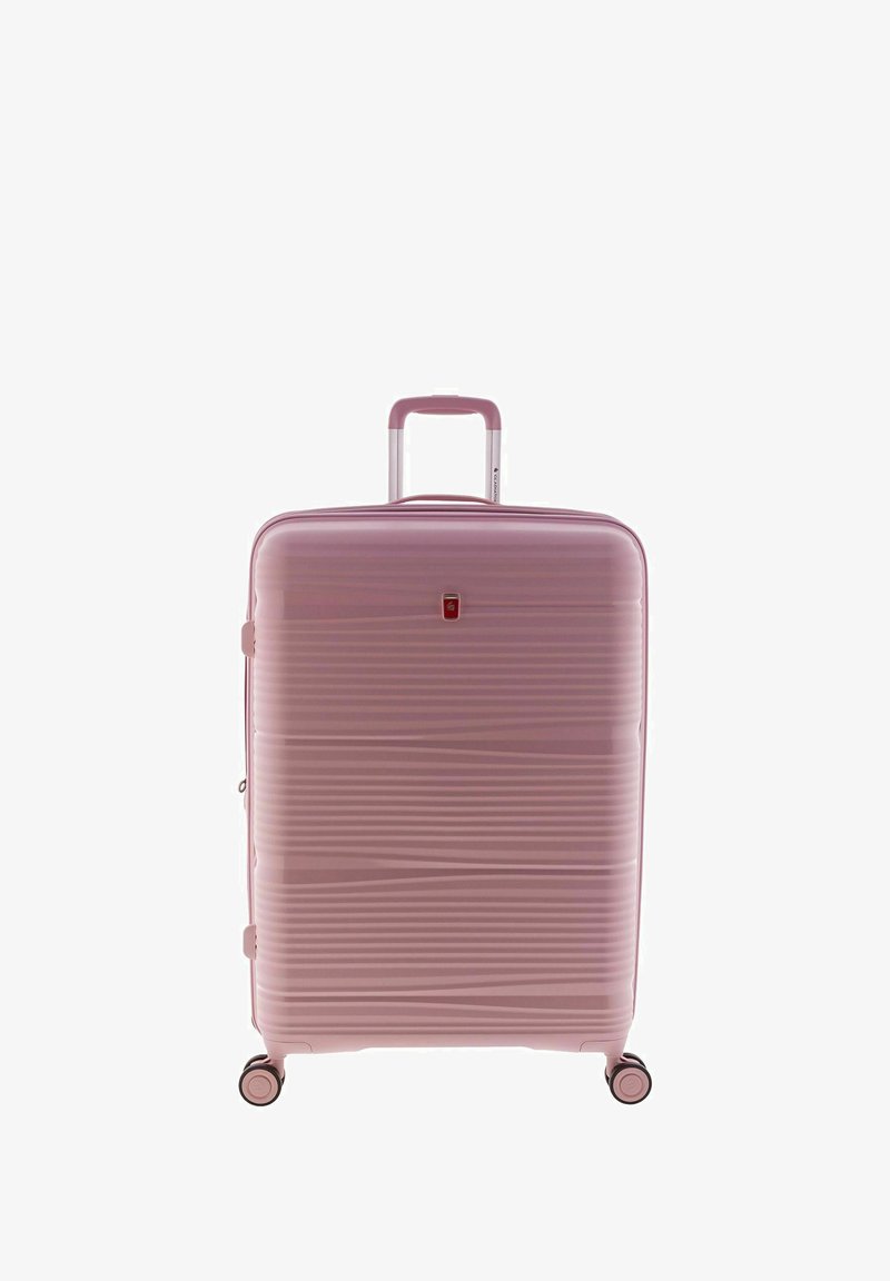 Valise rose à coque dure avec texture striée, poignée télescopique en aluminium et quatre roues noires pour la mobilité. Présente un petit détail de logo.