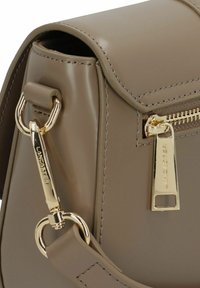 Borsa a mano in finta pelle marrone con texture liscia, accessori in oro e dettagli con cerniera. Presenta una forma strutturata e accenti cuciti.
