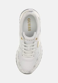 Zapatilla blanca con parte superior de cuero liso, detalles dorados y texturizados. Presenta cordones y una suela acolchada para mayor comodidad.