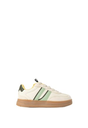 Baskets profil bas avec dessus beige, bandes latérales vertes et noires, doublure intérieure jaune et semelle en caoutchouc marron clair.