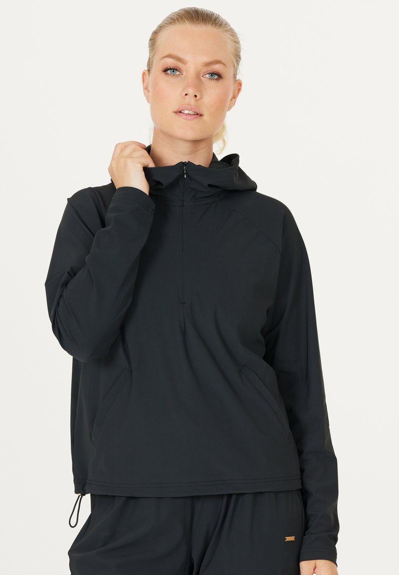 Pullover leggero nero con cappuccio, chiusura a zip quarti e tasche laterali. Caratterizzato da una vestibilità rilassata e una texture morbida. Decorato con un branding discreto.