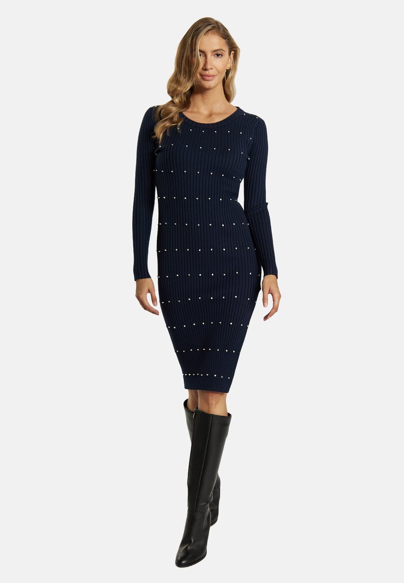 Marineblaues, geripptes Strickkleid mit langen Ärmeln, verziert mit verstreuten Perlenakzenten und einer figurbetonten Silhouette, kombiniert mit kniehohen schwarzen Stiefeln.