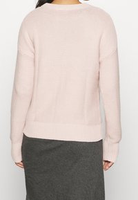 Jasnoróżowy sweter z dzianiny o luźnym kroju, z prążkowanymi mankietami i dołem, z teksturowanym wzorem i obniżonymi szwami na ramionach.