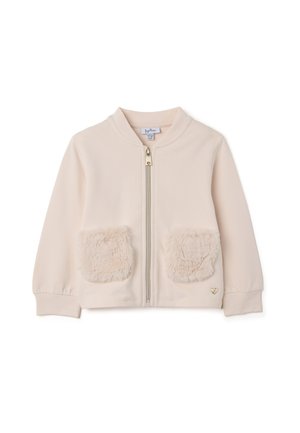 Giacca zip beige chiaro con morbide tasche in pelliccia sintetica, scollatura rotonda e polsini a costine. Presenta un sottile accento a forma di cuore vicino all'orlo.