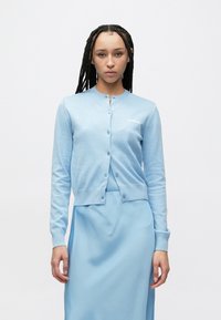 Jasnoniebieski kardigan wykonany z miękkiej dzianiny, z okrągłym dekoltem, zapięciem na guziki i subtelnym logo na piersi.