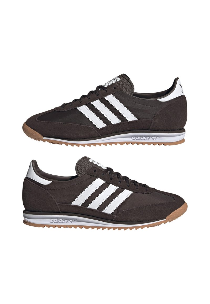 Chaussures de sport marron avec un design à trois bandes blanches, tige texturée, semelle en caoutchouc et languette légèrement rembourrée. Lacets plats et détail de logo.