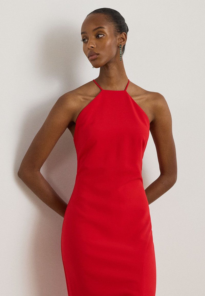 Κόκκινο φόρεμα με halter λαιμόκοψη και εφαρμοστή σιλουέτα, κατασκευασμένο από απαλό ύφασμα. Λεπτές ραφές και καθαρή λαιμόκοψη ενισχύουν το κομψό του σχέδιο.