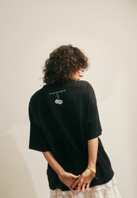 Zwarte oversized t-shirt met korte mouwen. Heeft witte letters en een kersengrafiek op de achterkant. Gemaakt van soepel katoen.