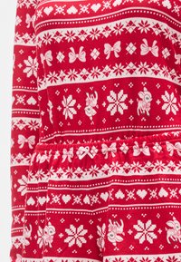 Rdeče oblačilo z vzorcem ponavljajočih se belih snežink, pentelj in jelenov. Elastičen pas z drobnim trakom kot dekorativnim elementom.