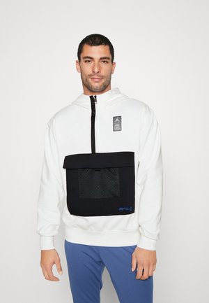 Felpa bianca con tasca a rete nera e pattina, caratterizzata da un'etichetta con logo e chiusura con zip. Il dettaglio in testo blu sulla tasca accentua il design.