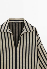 Beige shirt with black vertical stripes, open collar, and V-neck, made of textured fabric, displayed against a white background.