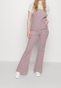 Ljusrosa kordbyxor med vida ben, sidofickor, randig skjorta under och vita sneakers. Texturerat tygmed detaljer.