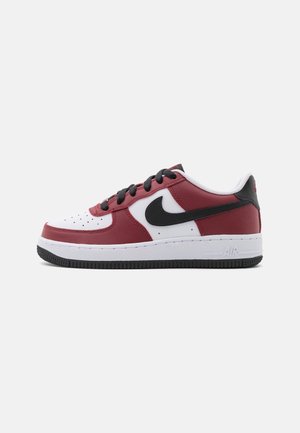 Niskie sneakersy z białej i bordowej skóry z czarnym logo Nike, czarnymi sznurowadłami, białą środkową podeszwą i czarną gumową spodem.