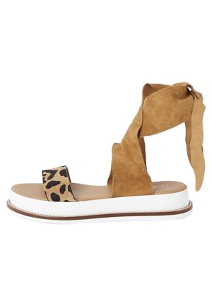 Tann mockasinsandal med leopardmönstrad rem, vit plattformssula och lång, vikbar ankelbindning. Slät läderfotbädd.