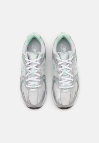 Zapatillas deportivas grises y menta con materiales de malla y sintéticos. Presentan cordones blancos, un collar acolchado y acentos texturizados en la parte superior.