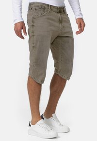 Lysbrune denimshorts med et afslappet fit, der har sidelommer, en knælang skæring og en falmet tekstur. Kombineret med hvide sneakers.