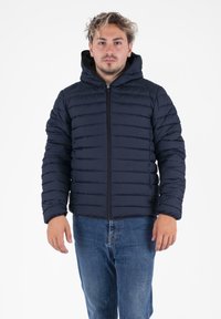Marine pufferjack met een horizontaal doorgestikte uitstraling, voorkant met rits en een aangehechte capuchon. Gecombineerd met blauwe jeans; gestructureerd, geïsoleerd materiaal.