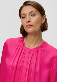 Fuchsia Langarmbluse mit Rundhalsausschnitt und Falten, seidig-glatter Textur und einem leicht lockeren Sitz. Einfaches, elegantes Design ohne Muster.