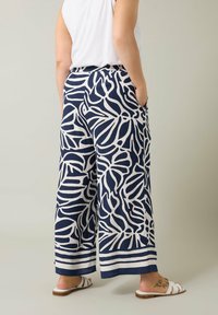 Pantalones de pierna ancha en un patrón de hojas en azul marino y blanco, con un corte relajado, cintura elástica y bolsillos laterales. Tejido ligero, diseño casual.