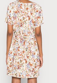 Robe à manches courtes, longueur genou, avec un imprimé floral orange, bleu et violet sur un fond clair ; dotée d'une taille ceinturée et d'une ouverture en forme de goutte d'eau dans le dos.