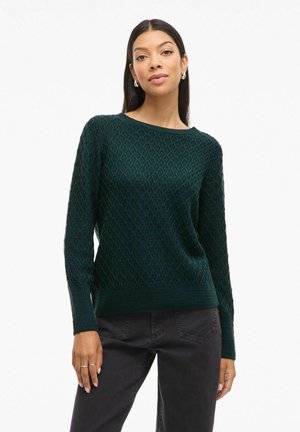 Pull en tricot vert foncé avec un motif en losanges, un col rond et des manches longues. Le tissu semble doux avec une finition texturée.
