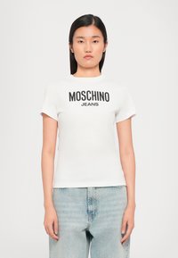 White cotton t-shirt with short sleeves, featuring a large black print reading "MOSCHINO JEANS" across the chest. Casual fit.
