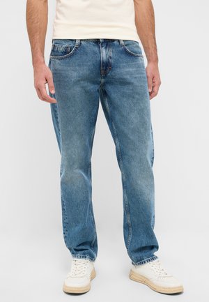 Light blue denim jeans with a straight leg fit. Features five pockets and subtle yellow stitching. Worn with white sneakers.