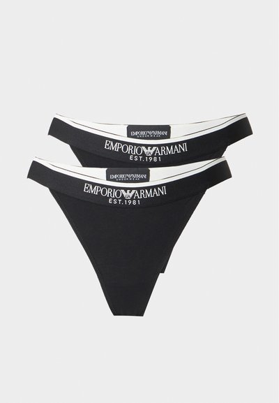 Δύο μαύρα γυναικεία στρινγκ Emporio Armani με λευκές ελαστικές ζώνες μέσης και κείμενο λογοτύπου "Emporio Armani Est. 1981" μπροστά.