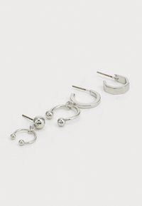 Ensemble de trois boucles d'oreilles en argent : deux paires de créoles avec des surfaces lisses et des accents sphériques, et un design hexagonal avec une finition polie.