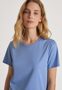 Lichtblauw t-shirt met korte mouwen, gemaakt van zachte stof. Heeft een ronde halslijn en een gladde textuur. Minimalistisch ontwerp zonder patronen.