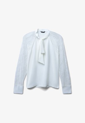 Blusa bianca con lunghe maniche in pizzo, colletto rotondo e dettaglio a fiocco al collo. Tessuto liscio con una leggera lucentezza.