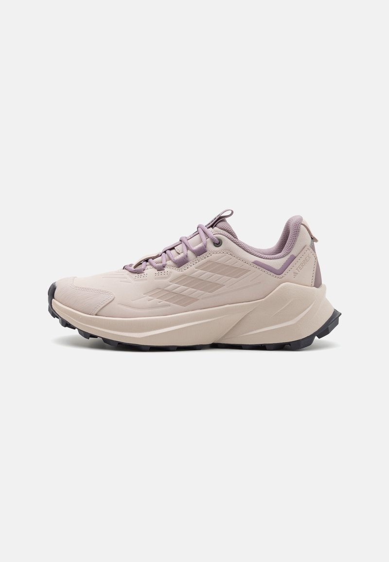 Sapatilha de trail running em rosa claro com um cabedal texturizado, colarinho acolchoado e uma sola de borracha preta com sulcos profundos para maior aderência.
