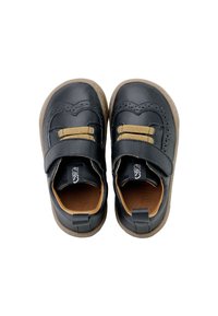 Zapatos de cuero negro con una correa de velcro, acentos marrones, detalles perforados y un interior beige con una suela de goma flexible.
