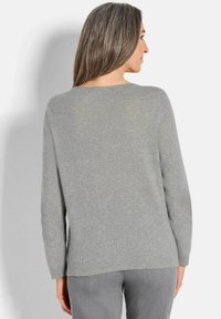 Grauer Strickpullover mit lockerer Passform, Rundhalsausschnitt und langen Ärmeln. Weicher Stoff mit einem etwas längeren Rückensaum.