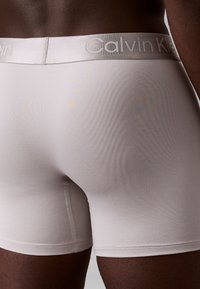 Boxers ajustados Calvin Klein de color gris claro con una tela suave y elástica; cuentan con una cintura cómoda y un diseño aerodinámico. Sin patrones visibles.