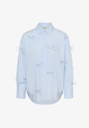 Camicia azzurra chiara con bottoni e maniche lunghe, decorata con numerosi piccoli fiocchi di tessuto cuciti sul davanti, sulle maniche e sulle spalle.