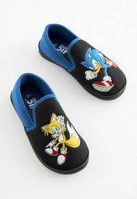 Melnas slip-on kurpes ar zilām elastīgām akcentiem. Ievērojamu dizainu ar Sonic un Tails izšuvumiem, ar teksturētu auduma augšdaļu un gumijas zoli.