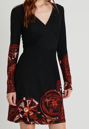 Vestido negro de manga larga con escote en V profundo y patrones abstractos circulares en rojo y naranja en las mangas y el dobladillo.