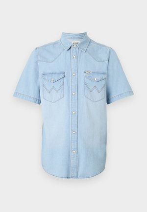 Svetlo modra denim s kratkimi rokavi s ovratnikom, z gumbki na pritisek in dvema žepoma na prsih, ki imata cik-cak šiv.