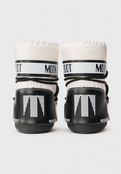 Een paar witte en zwarte Moon Boot winterlaarzen gezien vanaf de achterkant, met het logo en de veters om het enkelgebied gewikkeld.
