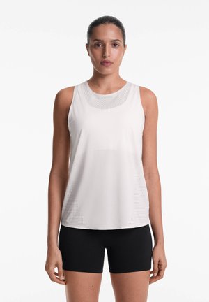 Top atletico bianco senza maniche con un motivo perforato, abbinato a pantaloni corti neri. La texture liscia e la vestibilità rilassata aumentano il comfort.