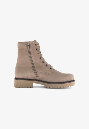 Beige suede ankle boots with a lace-up front and side zipper, featuring a chunky rubber sole and stitched detailing along the seams.