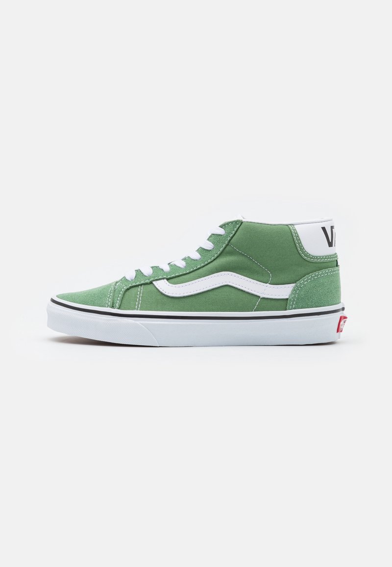 Baskets Vans mid-top vertes avec rayure latérale blanche, semelle blanche et lacets blancs sur fond clair uni.